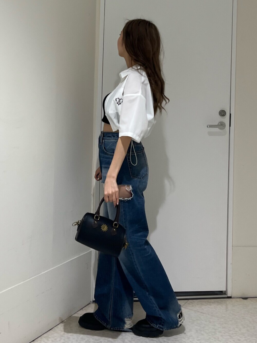 ブラック系のブーツ、ブルー系のデニムパンツ、その他のショルダーバッグを着用したレディースの春コーディネートの2枚目の写真