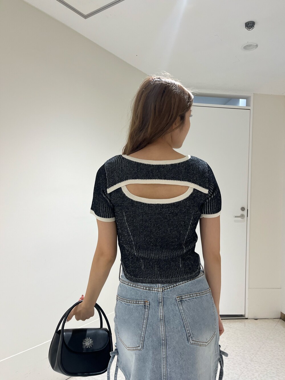 ブラック系のブーツ、ブルー系のデニムスカート、ブラック系のハンドバッグを着用したレディースの春コーディネートの6枚目の写真