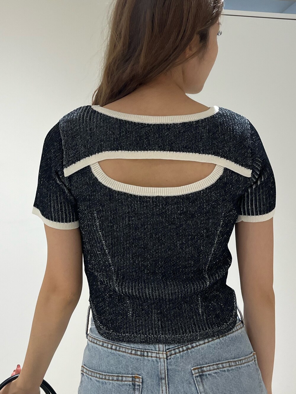 ブラック系のニット/セーター、ブルー系のデニムパンツ、その他のショルダーバッグを着用したレディースの春コーディネートの6枚目の写真