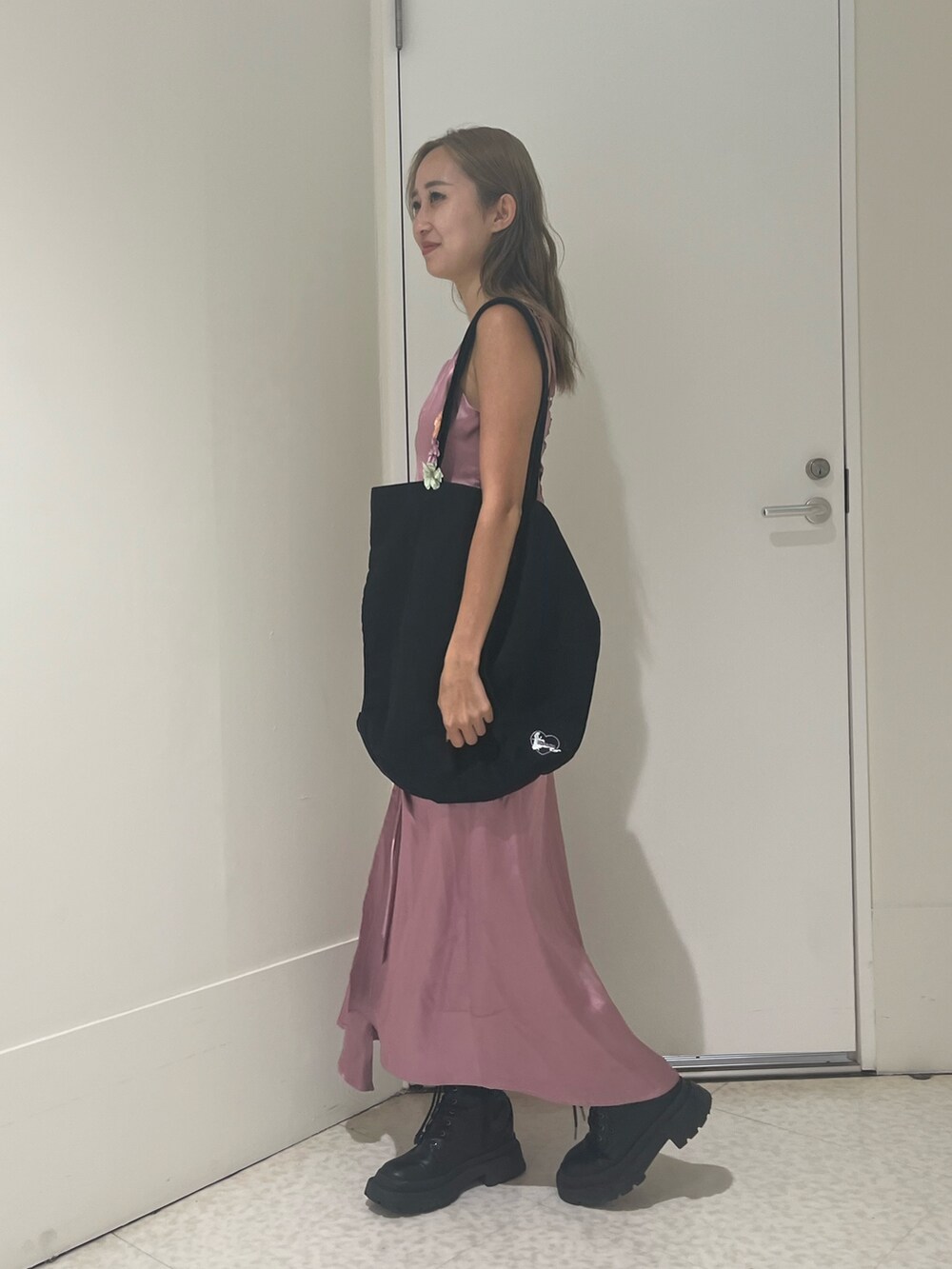 ピンク系のワンピース、ブラック系のトートバッグ、シルバー系のブーツを着用したレディースの夏コーディネートの2枚目の写真