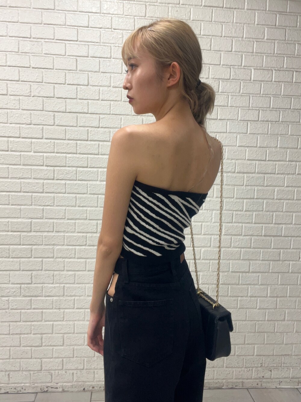 ホワイト系のサンダル、ブラック系のデニムパンツ、ブラック系のチューブトップを着用したレディースの秋コーディネートの6枚目の写真