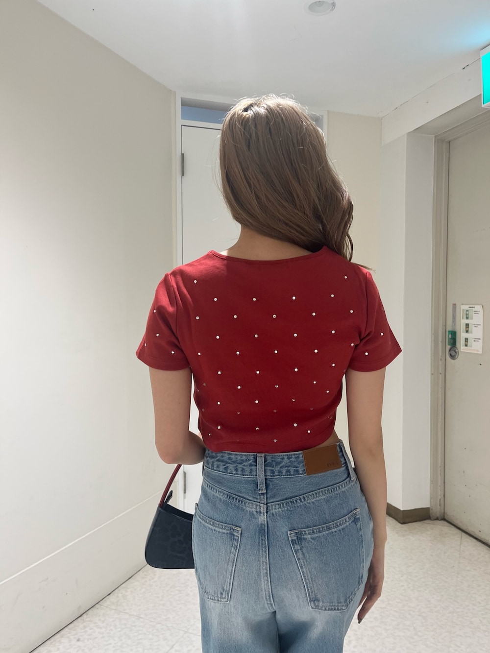 ブルー系のデニムパンツ、ブラウン系のハンドバッグ、ブラック系のブーツを着用したレディースの春コーディネートの5枚目の写真