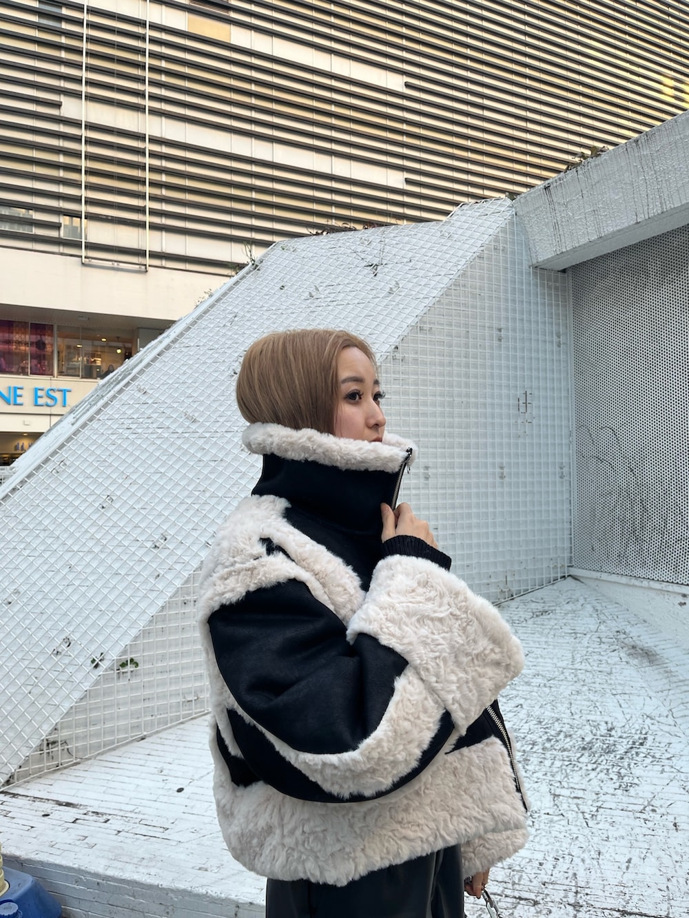 ブラック系のブーツ、シルバー系のショルダーバッグ、グリーン系のムートンコートを着用したレディースの冬コーディネートの4枚目の写真