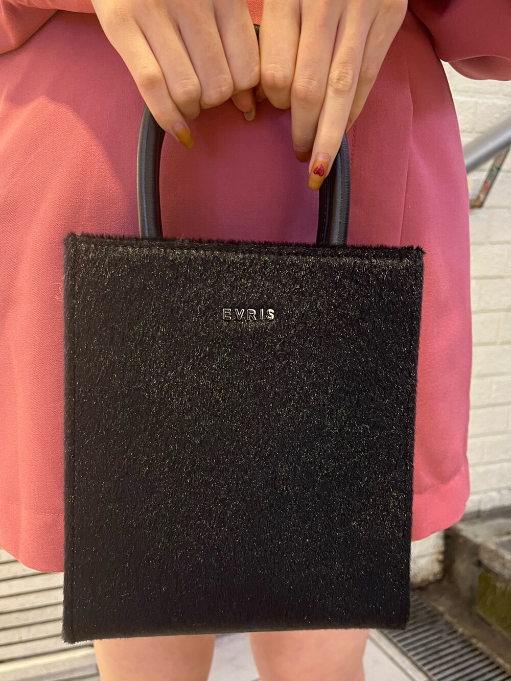 ブラック系のブーツ、ブラック系のショルダーバッグ、ピンク系のワンピースを着用したレディースの冬コーディネートの5枚目の写真