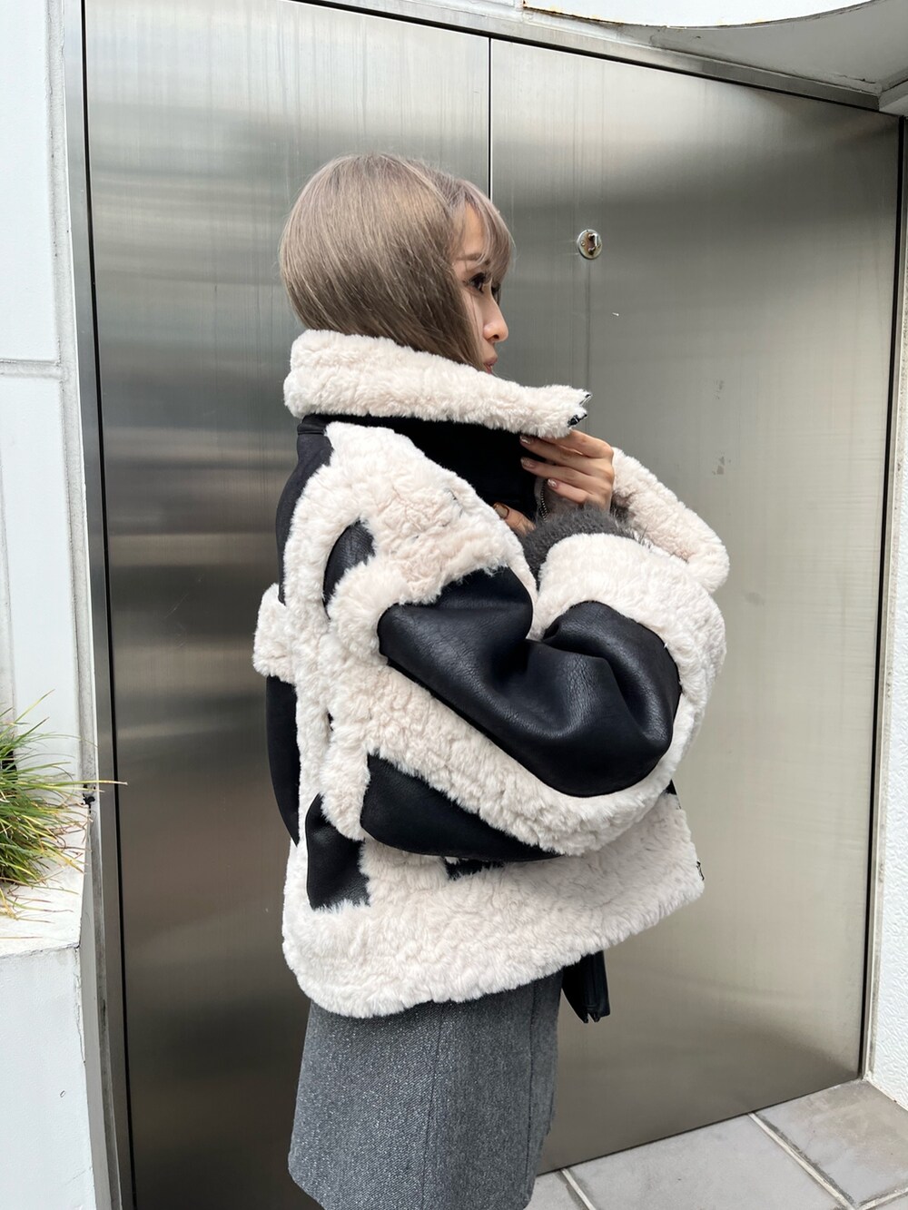 ブラック系のブーツ、ブラック系のショルダーバッグ、グリーン系のムートンコートを着用したレディースの冬コーディネートの5枚目の写真