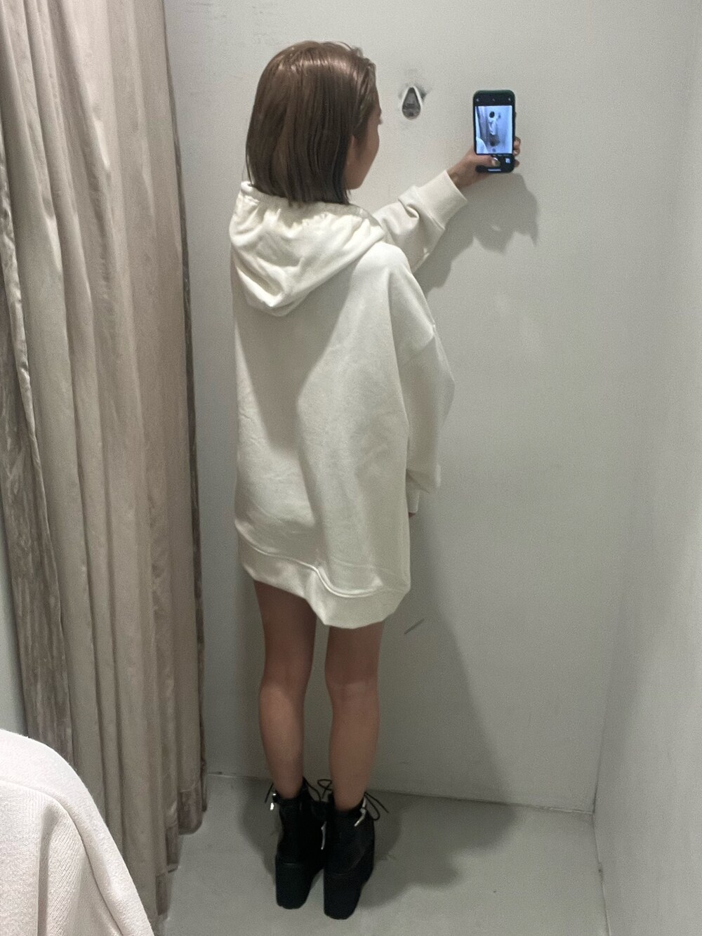 ホワイト系のパーカー、パープル系のスタジャン、ブラック系のブーツを着用したレディースの冬コーディネートの6枚目の写真