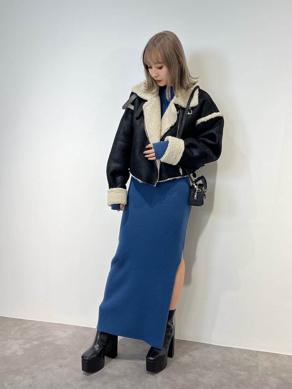 ブルー系のハンドバッグ、ブラック系のブーツ、ブルー系のワンピースを着用したレディースの冬コーディネートの10枚目の写真