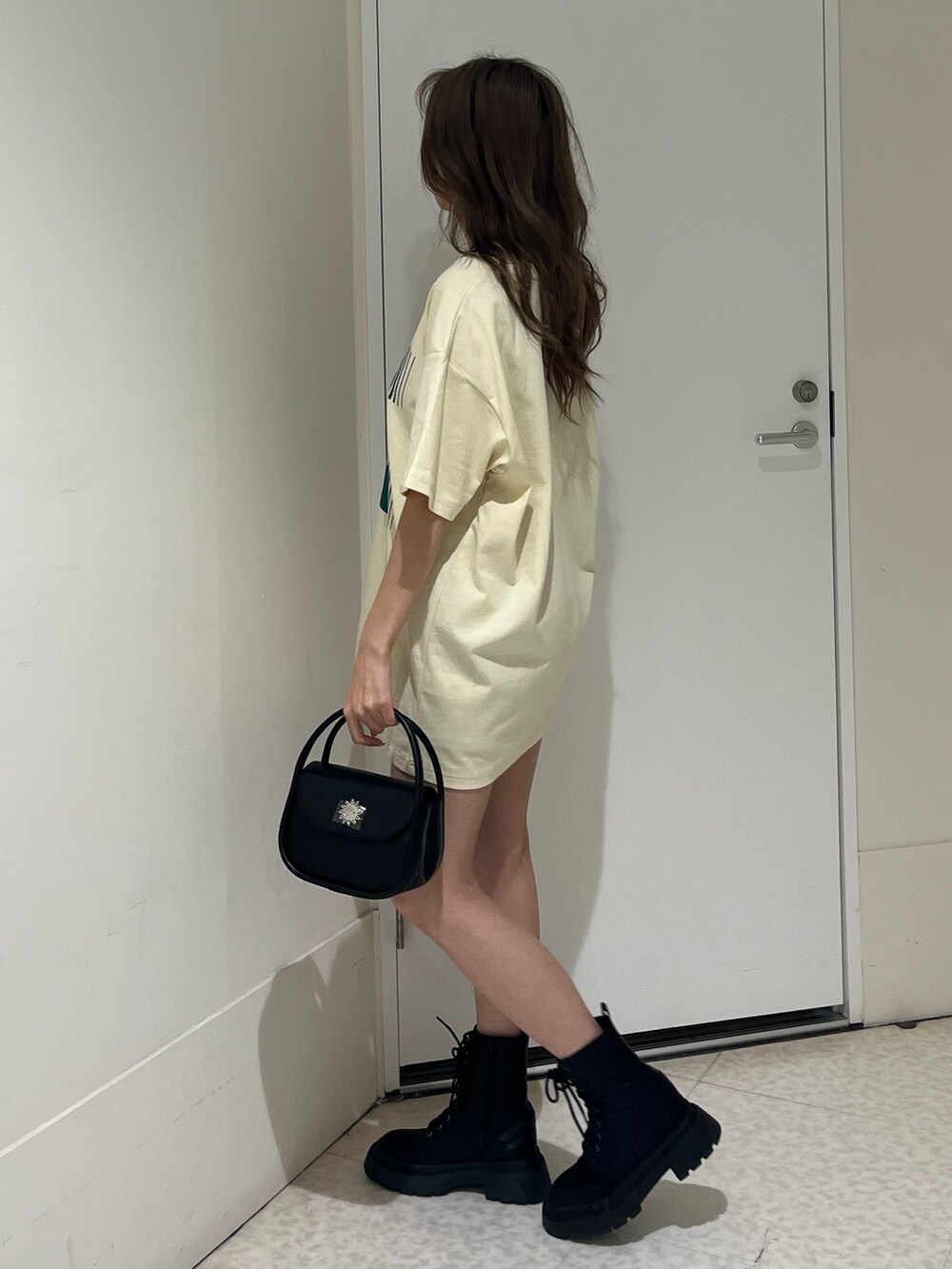 ブルー系のTシャツ/カットソー、ブラック系のハンドバッグ、ブラック系のブーツを着用したレディースの春コーディネートの2枚目の写真