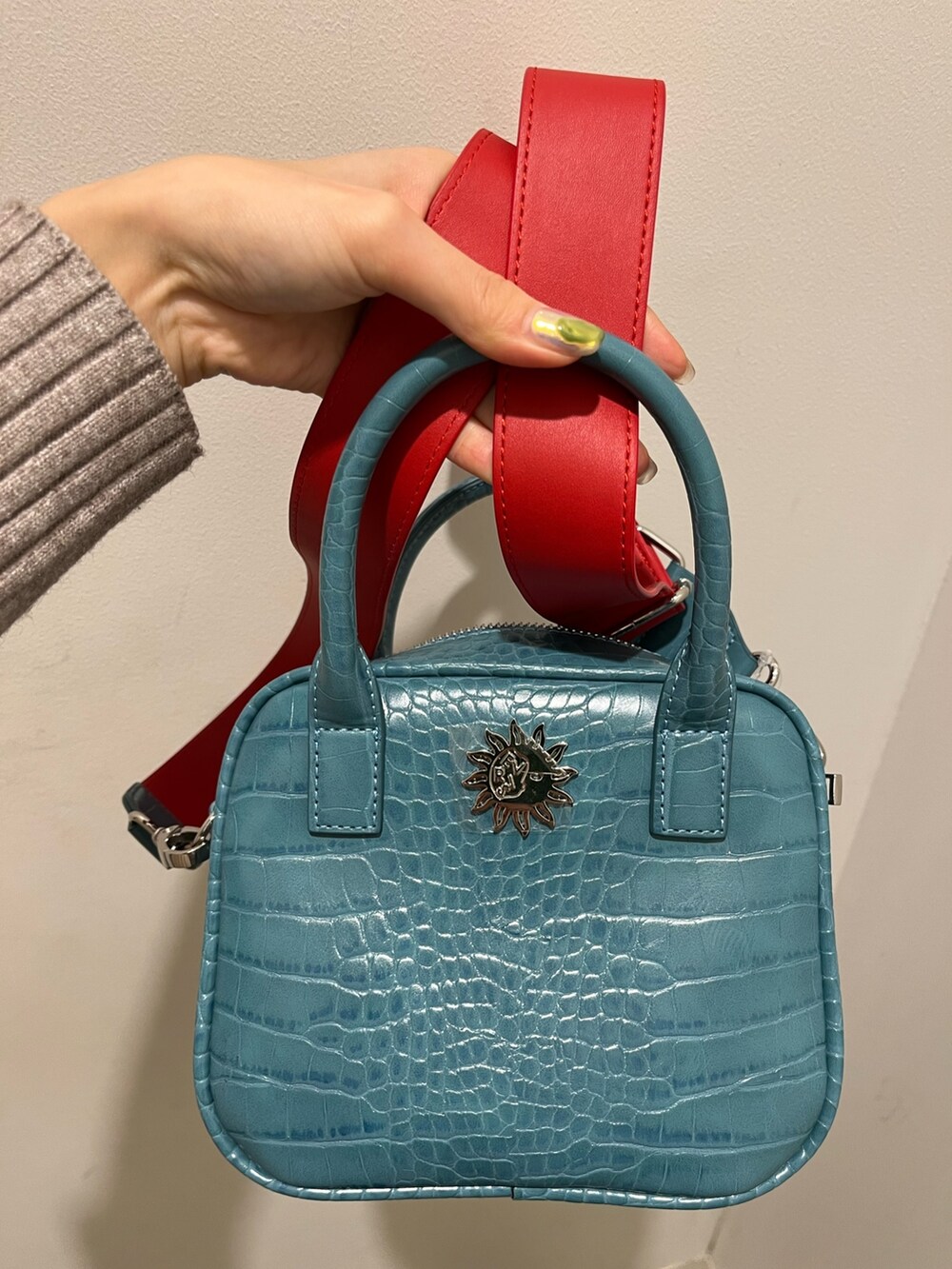 ブルー系のショルダーバッグ、ブラック系のブーツ、グレー系のニット/セーターを着用したレディースの冬コーディネートの5枚目の写真