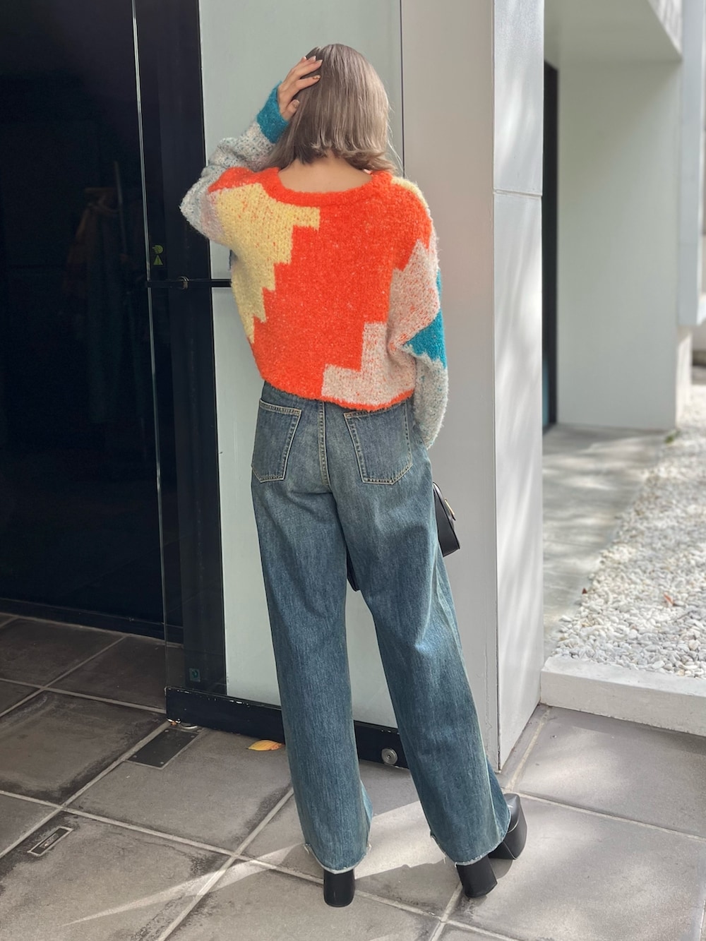 ブラック系のボストンバッグ、ブルー系のニット/セーター、ブルー系のデニムパンツを着用したレディースの冬コーディネートの5枚目の写真