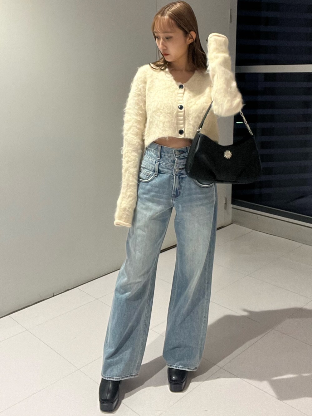 ブルー系のデニムパンツ、ブラック系のハンドバッグ、ホワイト系のニット/セーターを着用したレディースの秋コーディネートの8枚目の写真