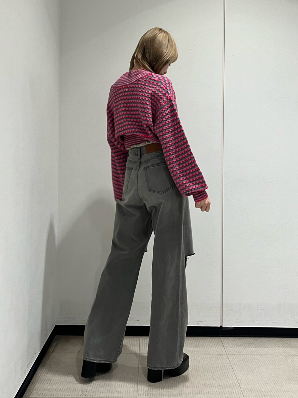 ブラック系のデニムパンツ、ピンク系のカーディガン/ボレロ、ブラック系のブーツを着用したレディースの冬コーディネートの4枚目の写真