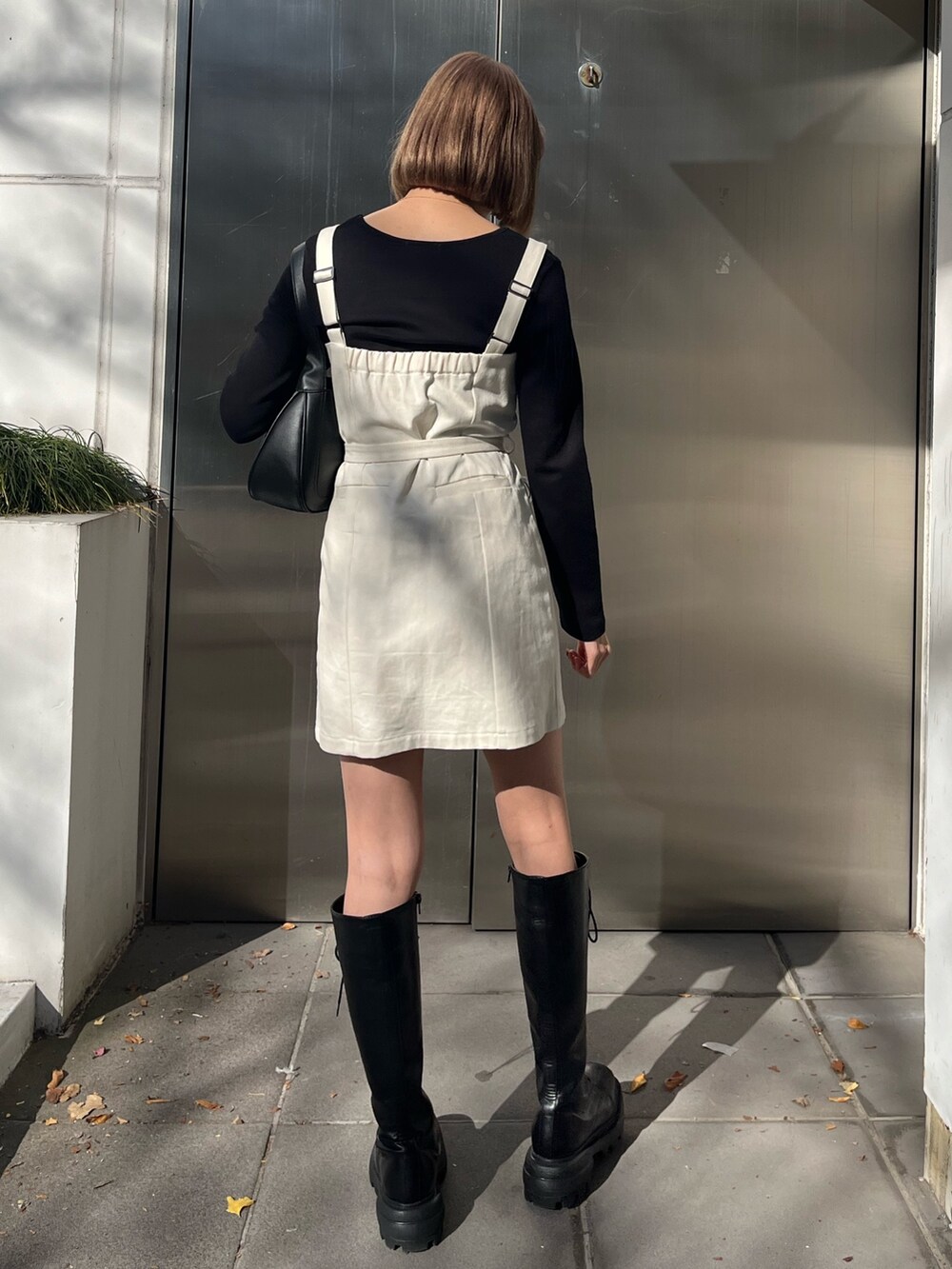 ブラック系のワンピース、ブラック系のハンドバッグ、ブラック系のブーツを着用したレディースの冬コーディネートの3枚目の写真