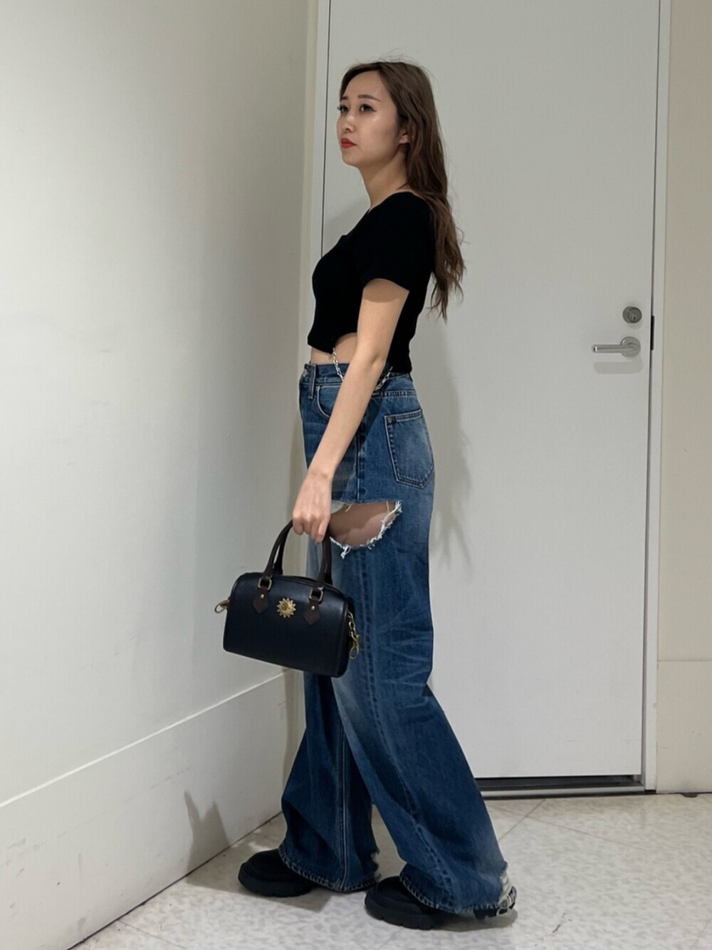 ブラック系のブーツ、ブルー系のデニムパンツ、その他のショルダーバッグを着用したレディースの春コーディネートの2枚目の写真