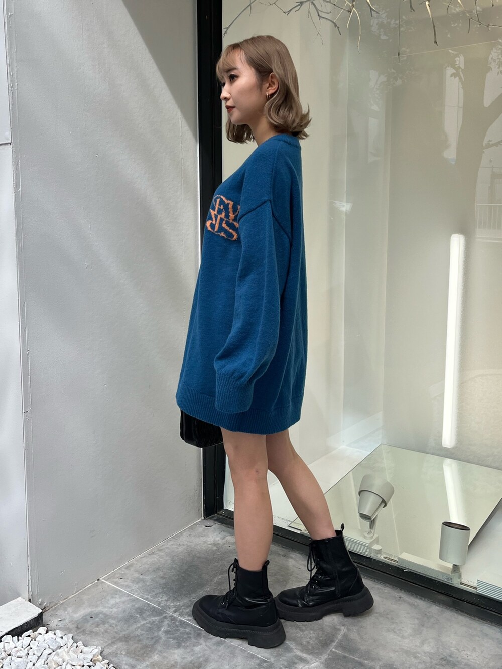 シルバー系のショルダーバッグ、ホワイト系のブーツ、ブルー系のニット/セーターを着用したレディースの秋コーディネートの8枚目の写真