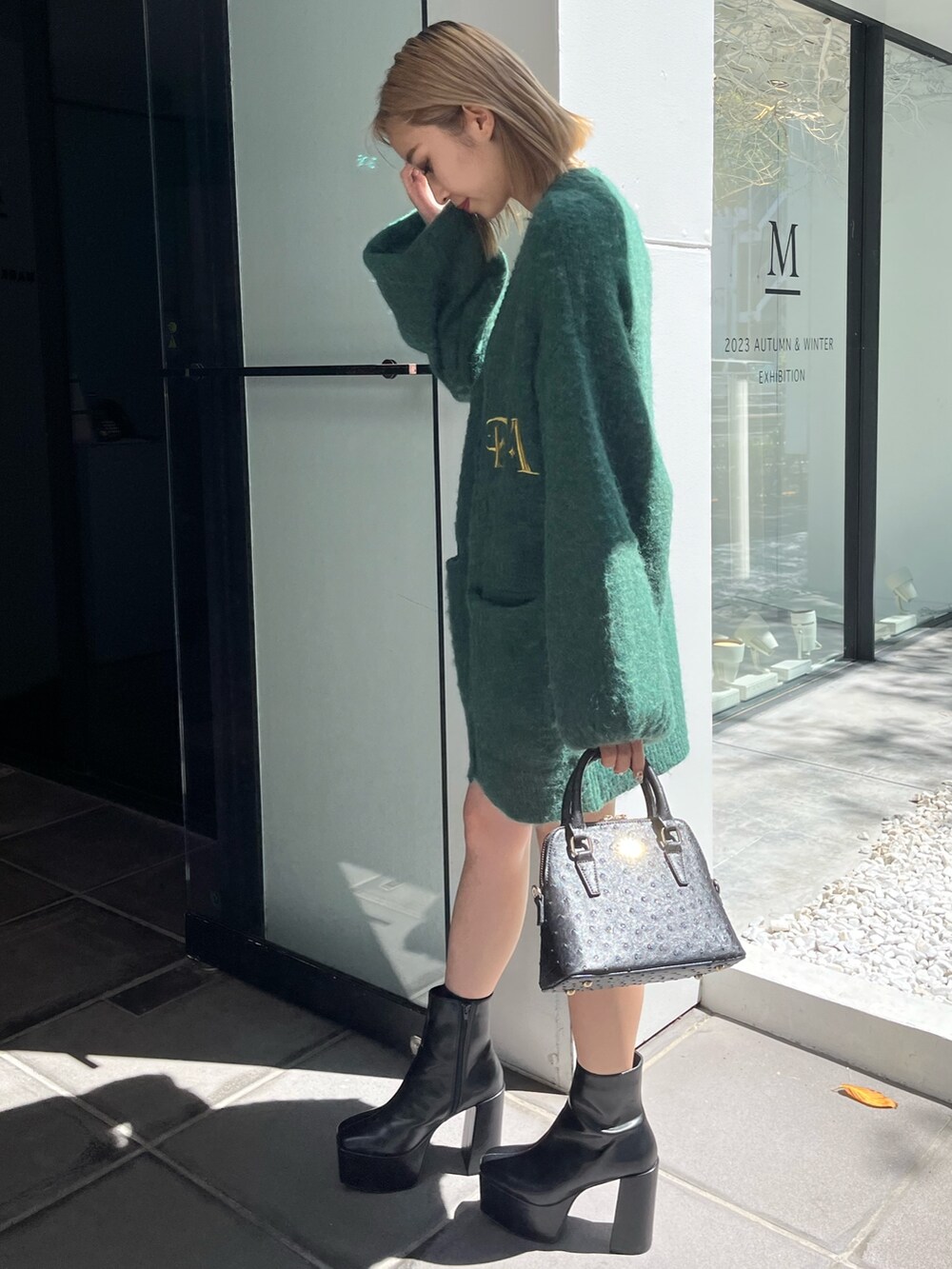 ブラック系のブーツ、ブラック系のショルダーバッグ、グリーン系のカーディガン/ボレロを着用したレディースの秋コーディネートの2枚目の写真