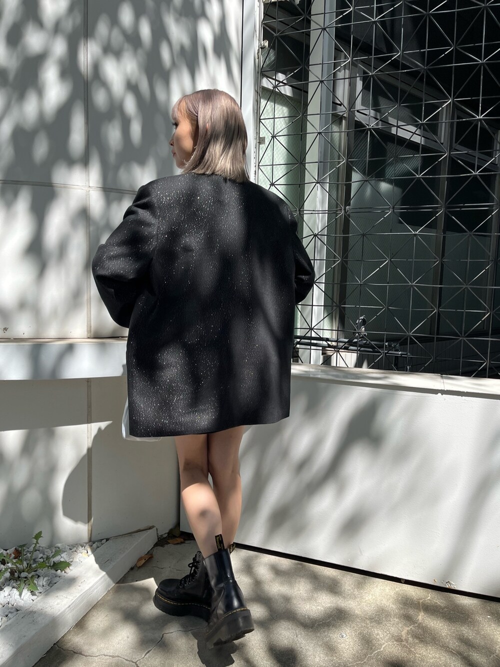 ブラック系のテーラードジャケット、ブラック系のスカート、ブラック系のブーツを着用したレディースの秋コーディネートの3枚目の写真