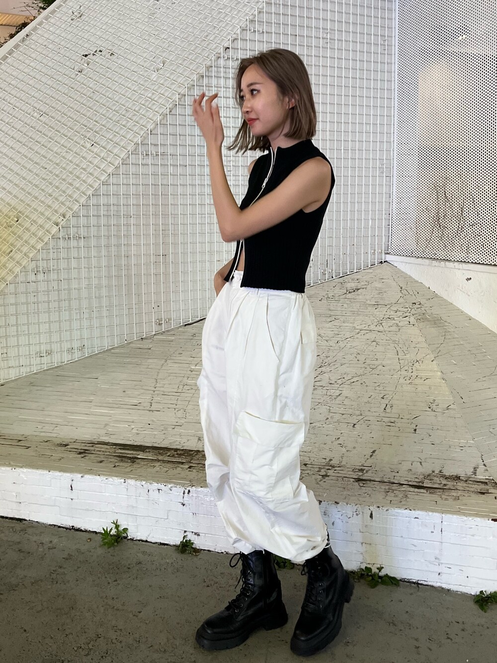 ホワイト系のカーゴパンツ、ブラック系のタンクトップ、ホワイト系のブーツを着用したレディースの夏コーディネートの4枚目の写真