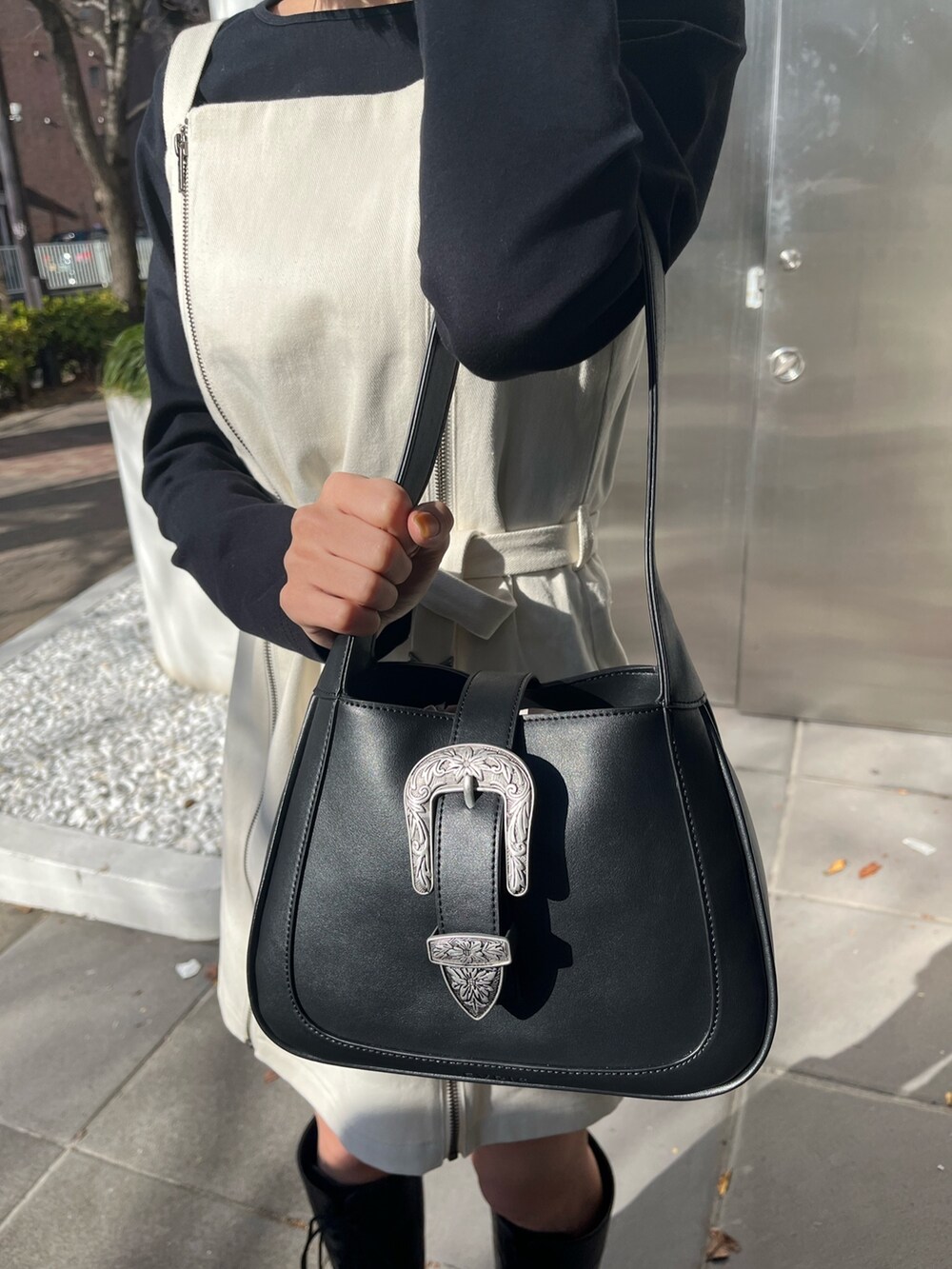 ブラック系のワンピース、ブラック系のハンドバッグ、ブラック系のブーツを着用したレディースの冬コーディネートの5枚目の写真