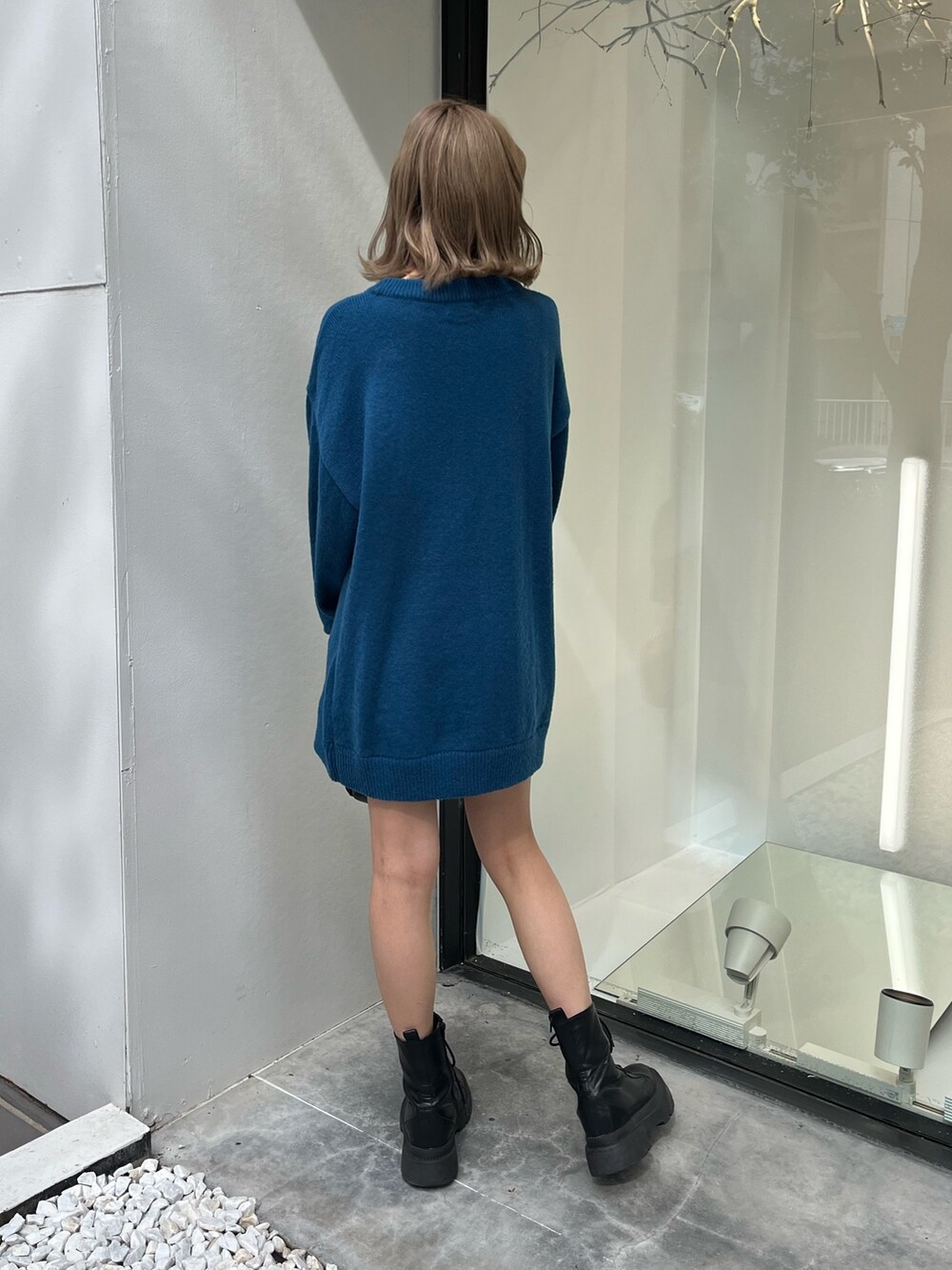 シルバー系のショルダーバッグ、ホワイト系のブーツ、ブルー系のニット/セーターを着用したレディースの秋コーディネートの3枚目の写真