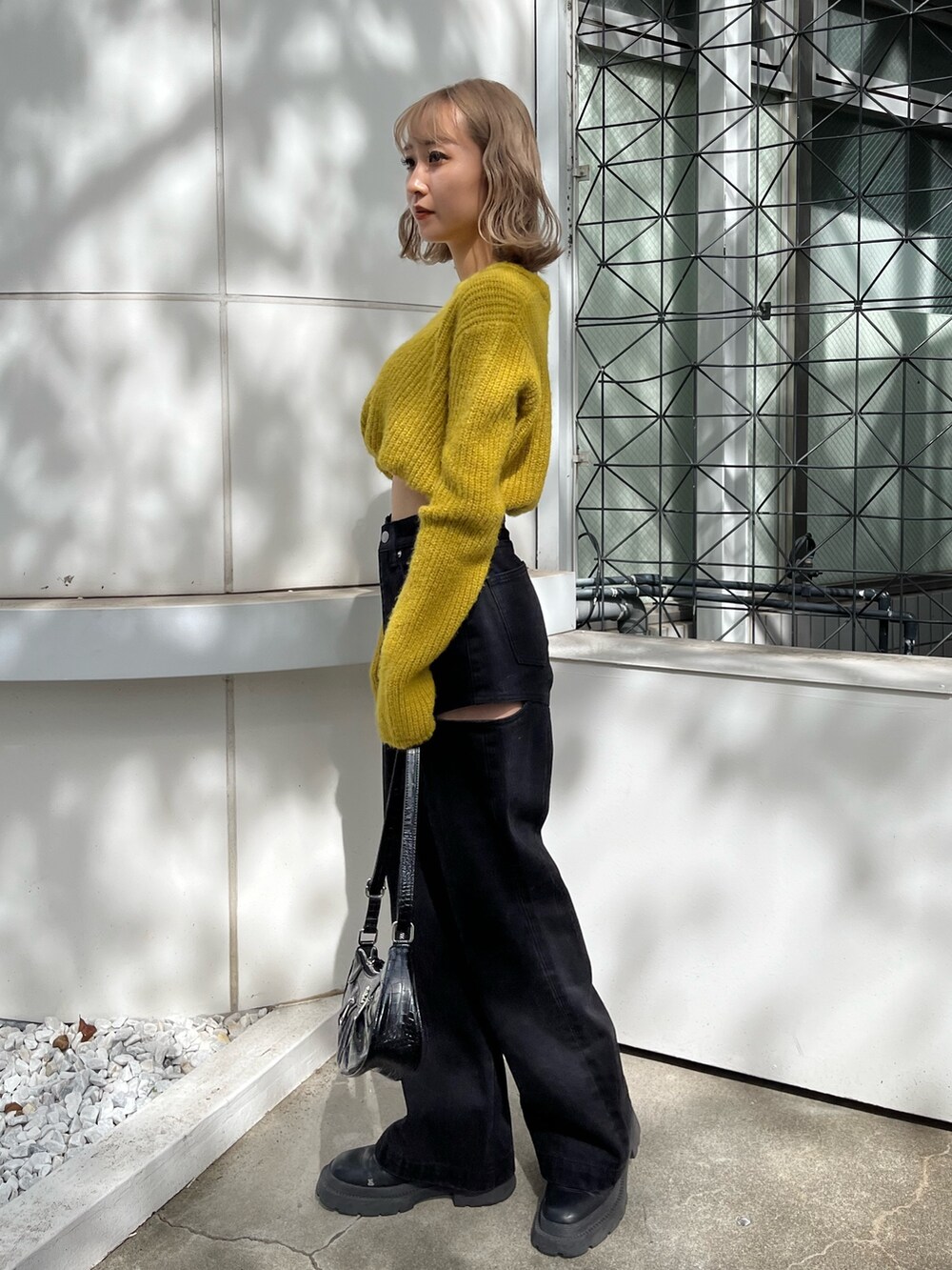 ブラック系のショルダーバッグ、ブラック系のデニムパンツ、イエロー系のニット/セーターを着用したレディースの秋コーディネートの3枚目の写真