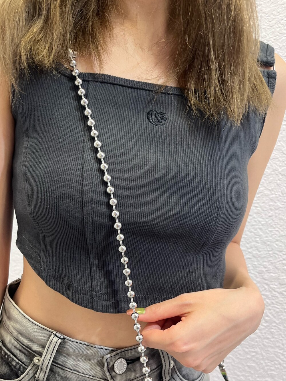 シルバー系のスカート、グレー系のキャミソール、シルバー系のブーツを着用したレディースの夏コーディネートの7枚目の写真