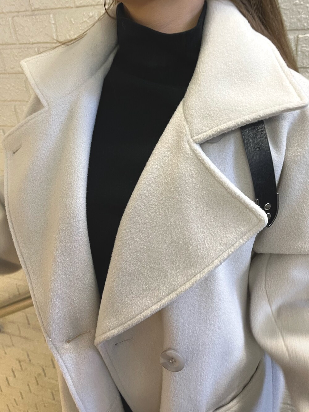 ホワイト系のその他アウター、ブラック系のその他パンツ、ブラック系のショルダーバッグを着用したレディースの冬コーディネートの5枚目の写真