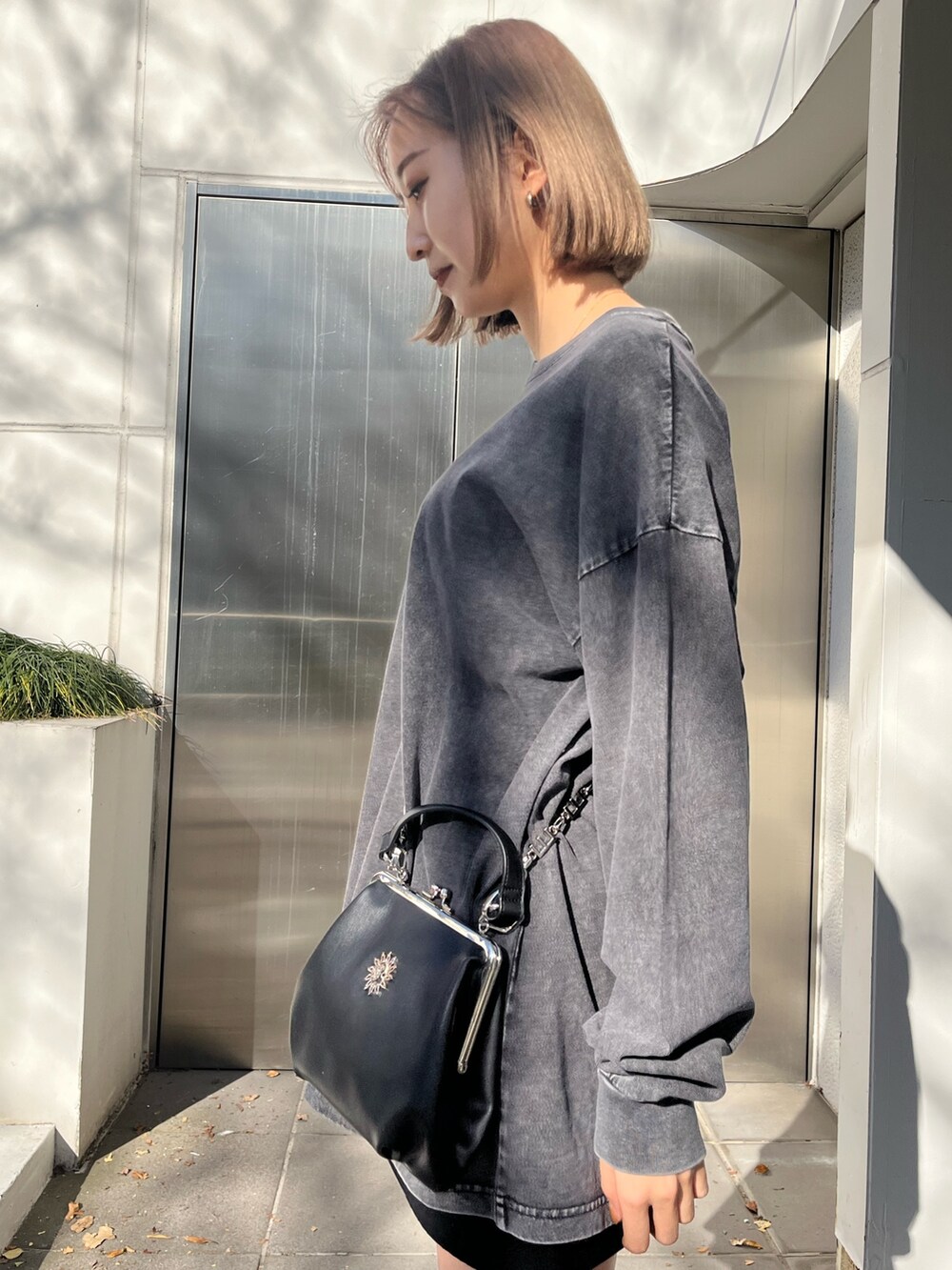 グレー系のTシャツ/カットソー、ブラック系のショルダーバッグ、ブラック系のブーツを着用したレディースの冬コーディネートの4枚目の写真