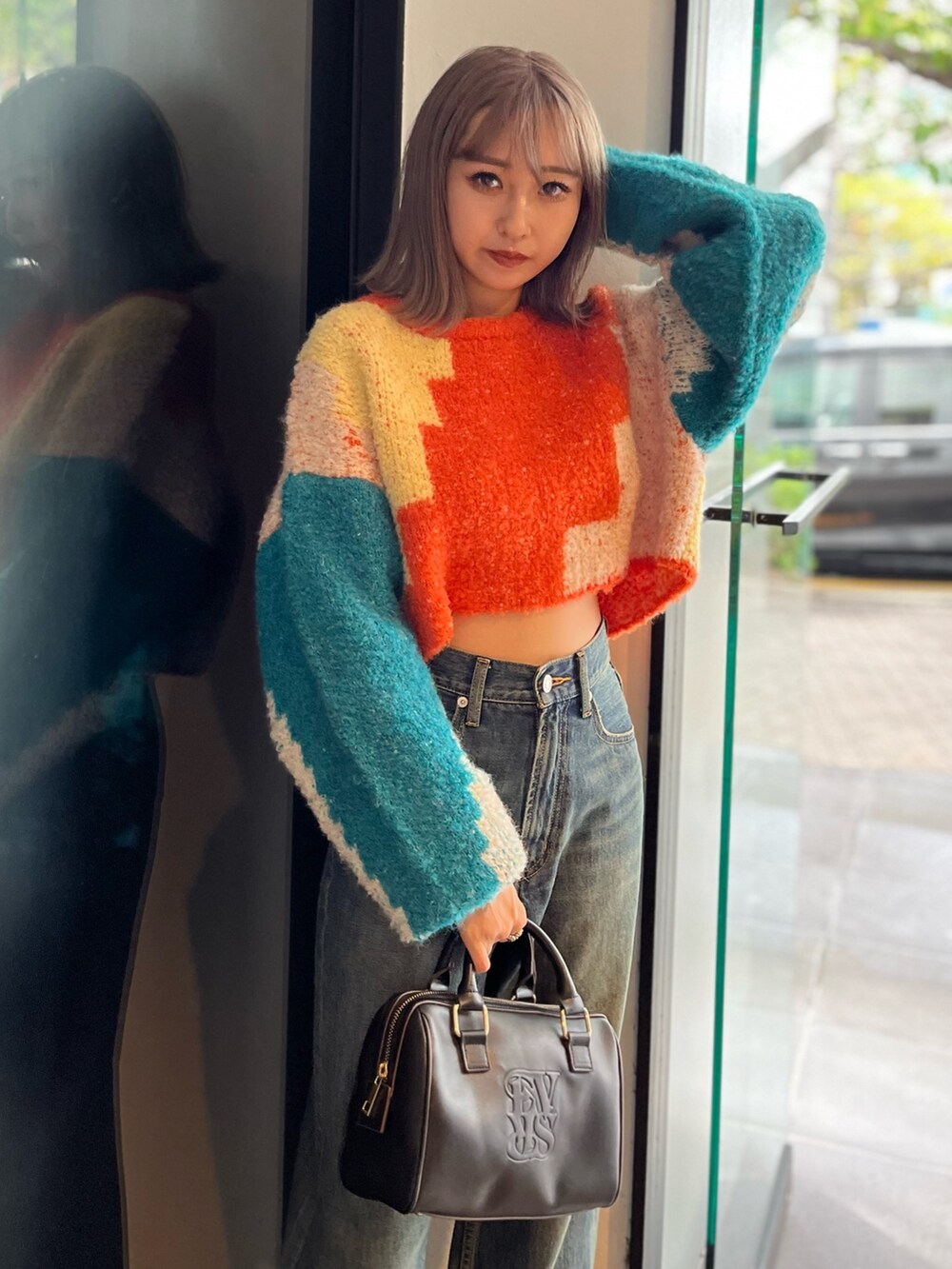 ブラック系のボストンバッグ、ブルー系のニット/セーター、ブルー系のデニムパンツを着用したレディースの冬コーディネートの6枚目の写真