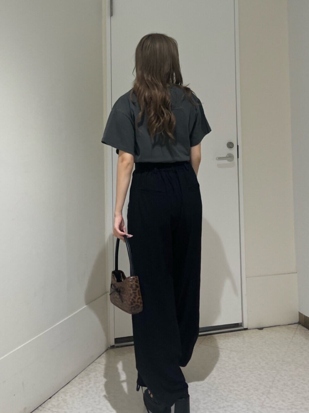 ブラウン系のハンドバッグ、ブラック系のサンダル、ブラック系のTシャツ/カットソーを着用したレディースの夏コーディネートの3枚目の写真