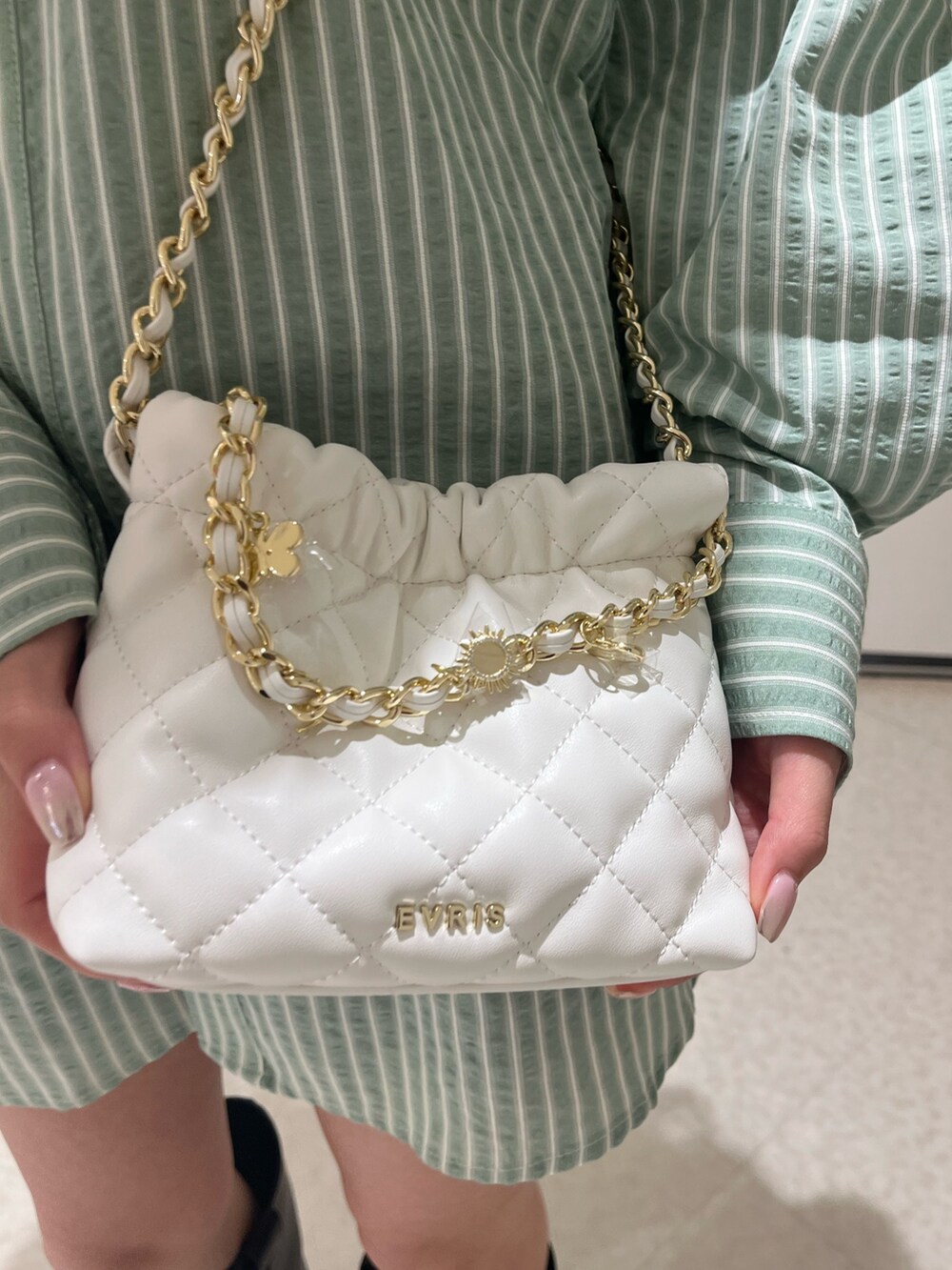 グリーン系のシャツ/ブラウス、ホワイト系のショルダーバッグ、ブラック系のブーツを着用したレディースの春コーディネートの6枚目の写真