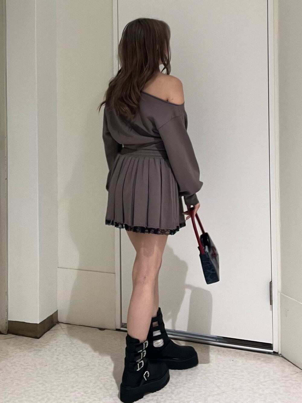 ブラック系のスウェット、ブラック系のスカート、ブラウン系のハンドバッグを着用したレディースの春コーディネートの2枚目の写真