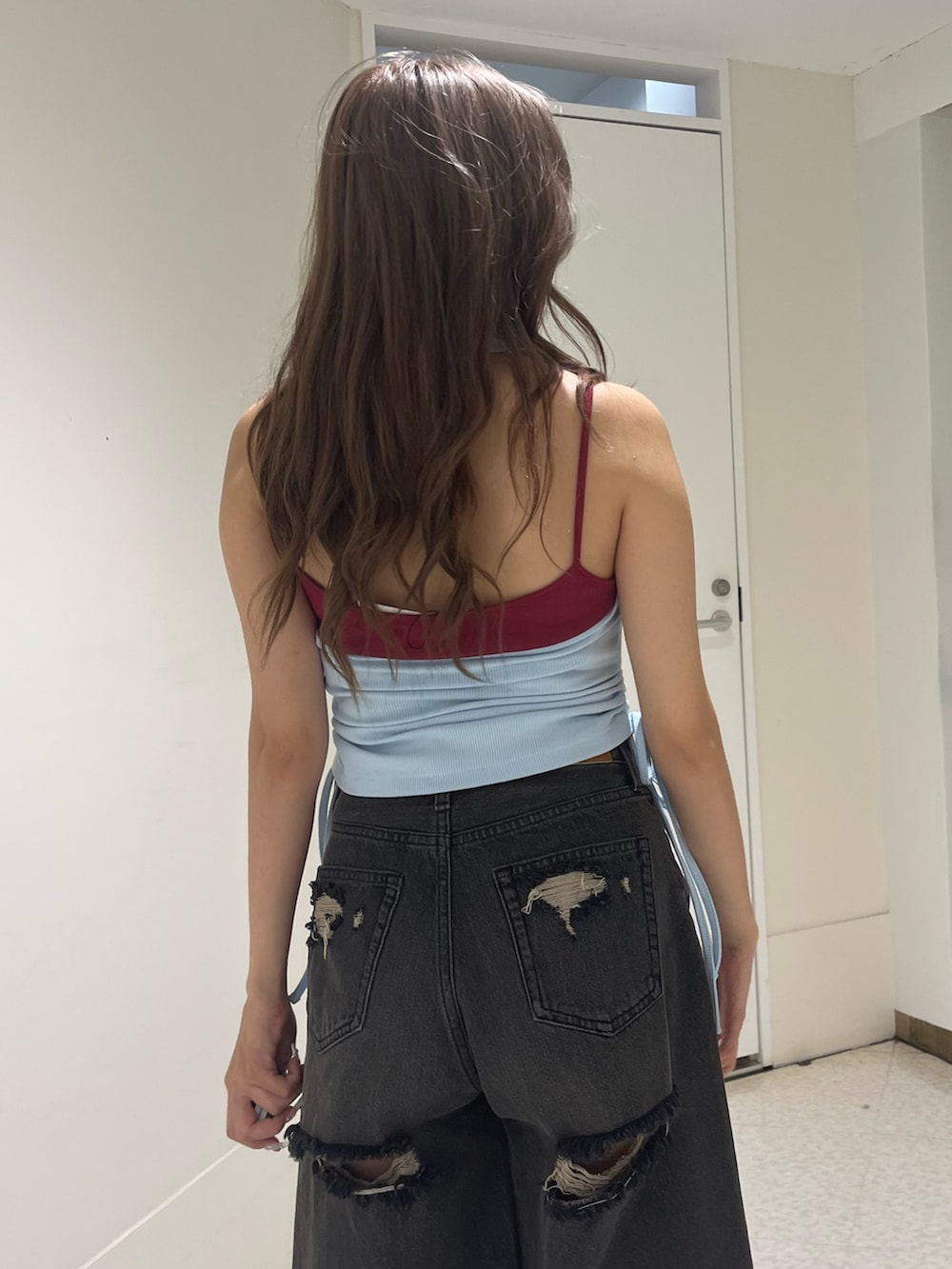 ブルー系のタンクトップ、ブラック系のデニムパンツ、ブラック系のブーツを着用したレディースの夏コーディネートの4枚目の写真