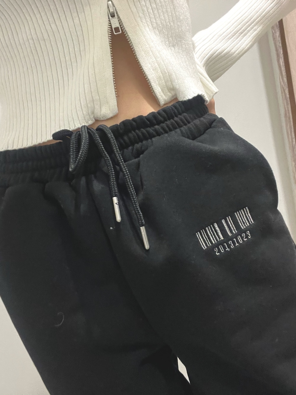 ブラック系のスウェットパンツ、ホワイト系のブーツ、ホワイト系のニット/セーターを着用したレディースの冬コーディネートの4枚目の写真