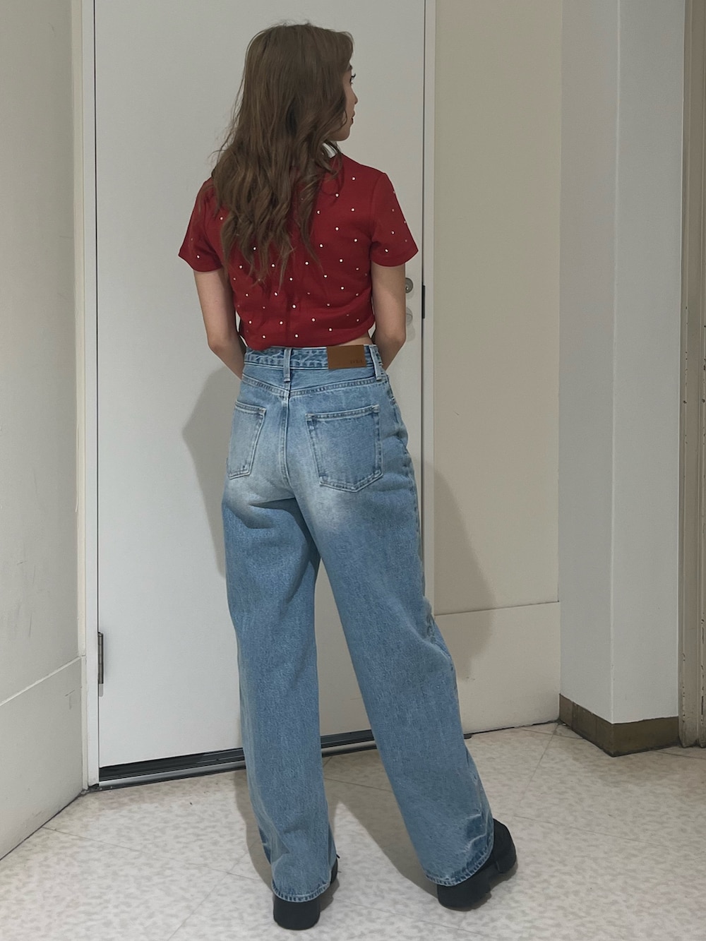 ブルー系のデニムパンツ、ブラウン系のハンドバッグ、ブラック系のブーツを着用したレディースの春コーディネートの3枚目の写真