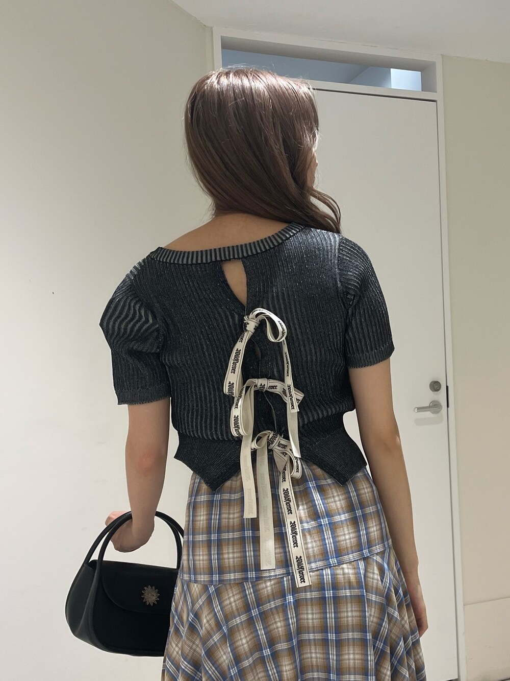 ベージュ系のスカート、ブラック系のハンドバッグ、ブラック系のサンダルを着用したレディースの夏コーディネートの5枚目の写真