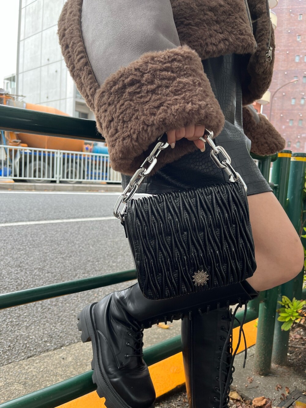 シルバー系のショルダーバッグ、ブラック系のワンピース、ブラック系のブーツを着用したレディースの秋コーディネートの5枚目の写真
