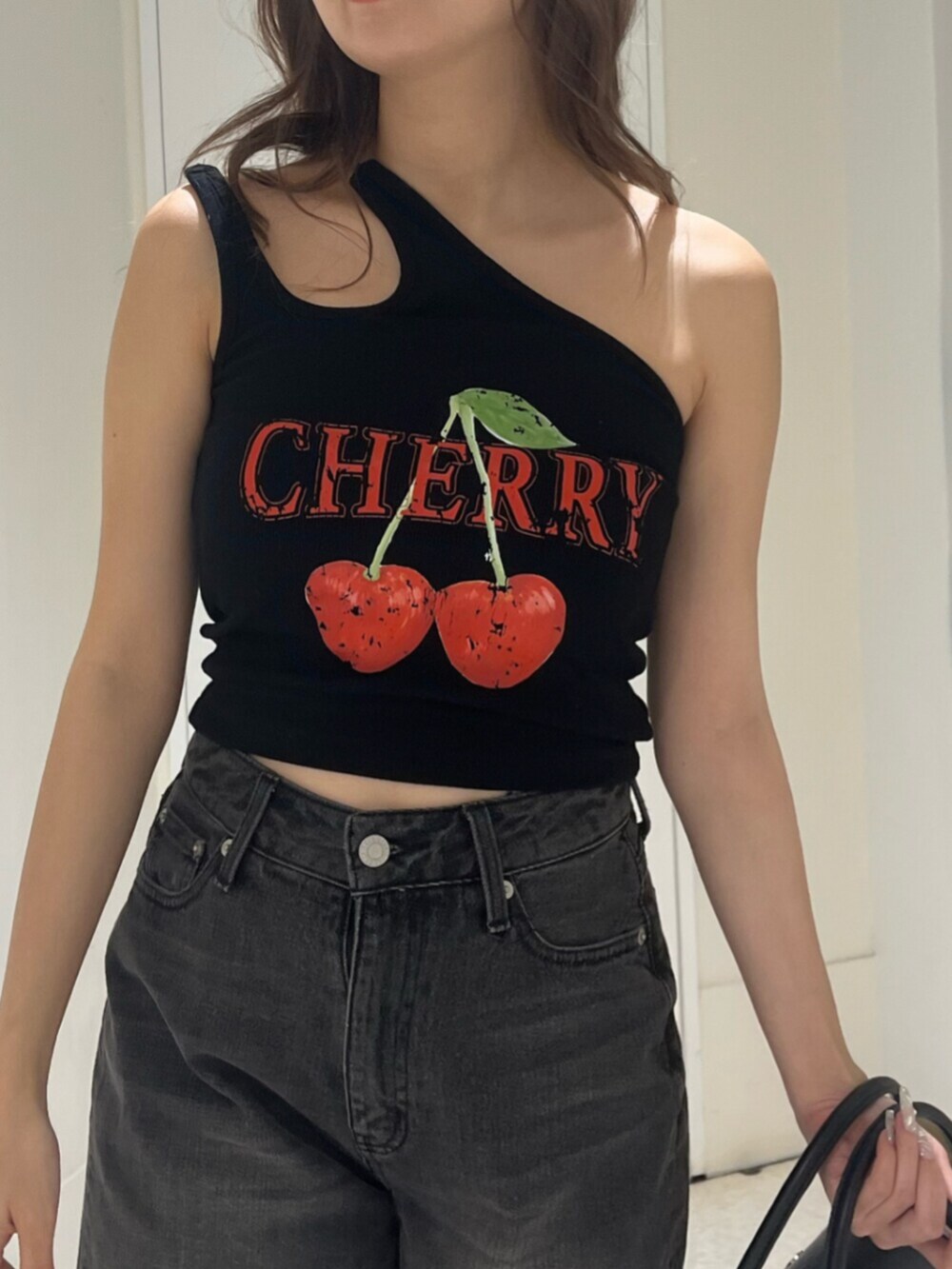 ブラック系のブーツ、ブラック系のハンドバッグ、ブラック系のデニムパンツを着用したレディースの夏コーディネートの4枚目の写真