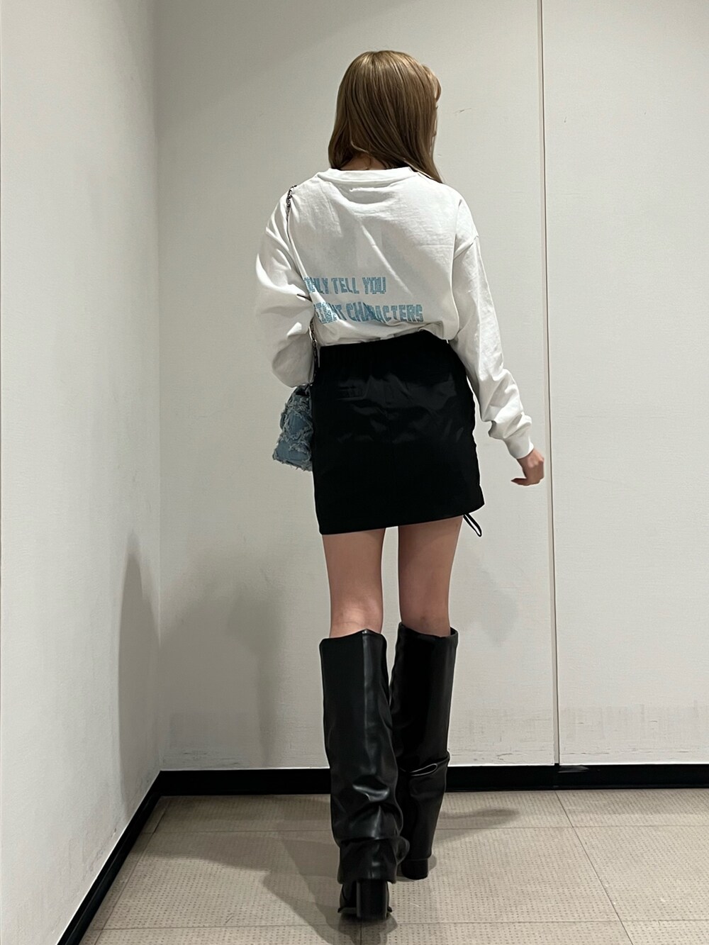 ホワイト系のブーツ、ブルー系のショルダーバッグ、ホワイト系のTシャツ/カットソーを着用したレディースの冬コーディネートの2枚目の写真