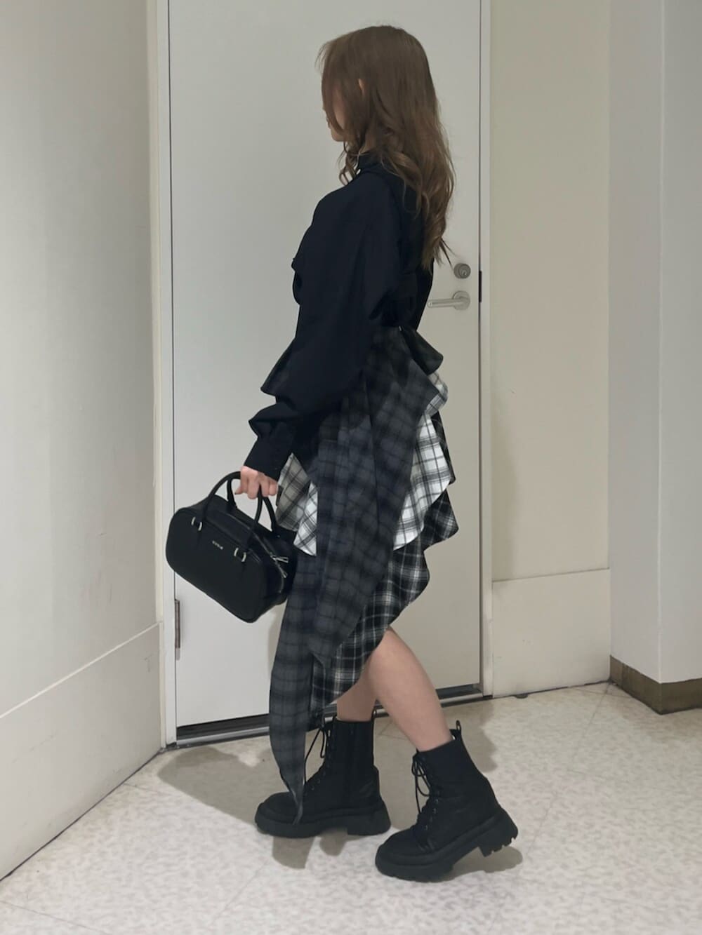 ブラック系のブーツ、ブラック系のボストンバッグ、ブラック系のスカートを着用したレディースの春コーディネートの2枚目の写真