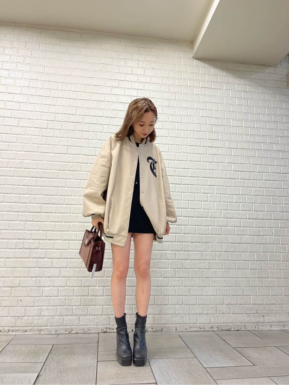 ブラック系のワンピース、ブラック系のブーツ、ベージュ系のブルゾンを着用したレディースの秋コーディネートの2枚目の写真