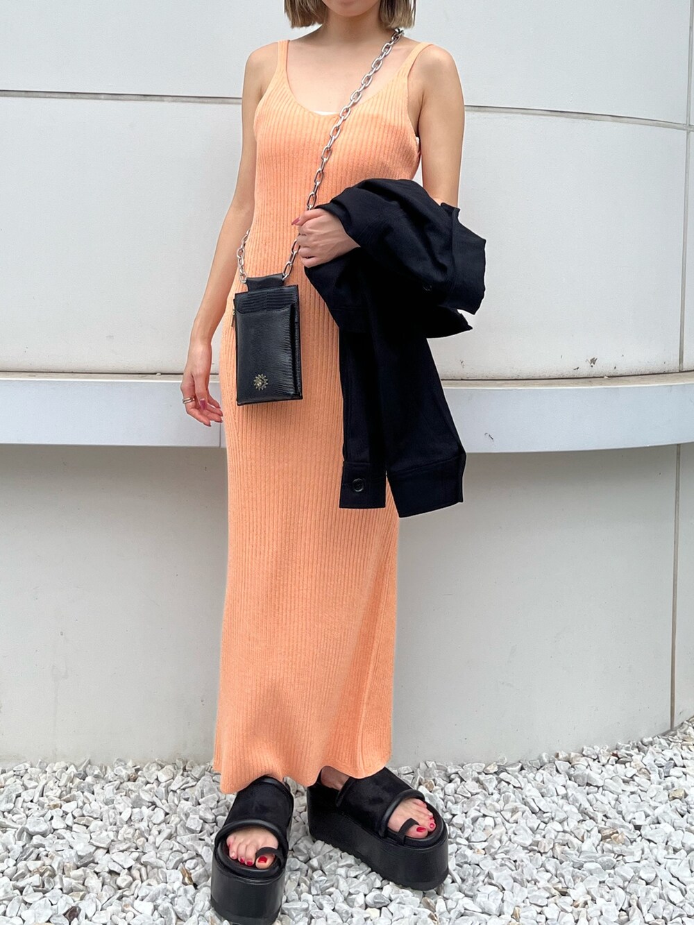 ブラック系のサンダル、ブラック系のミリタリージャケット、オレンジ系のワンピースを着用したレディースの春コーディネートの2枚目の写真