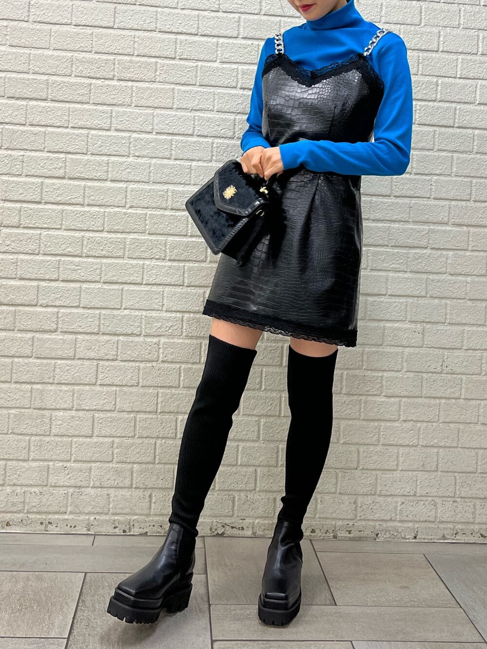 ブラック系のブーツ、ブラック系のワンピース、ブルー系のTシャツ/カットソーを着用したレディースの秋コーディネートの2枚目の写真