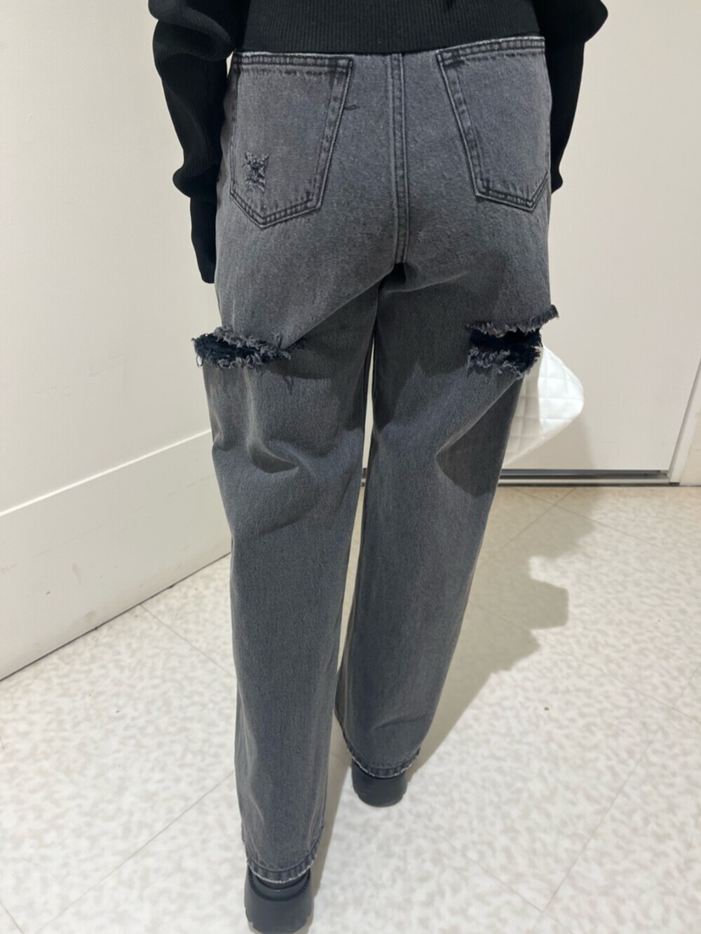 ブラック系のブーツ、ブラウン系のハンドバッグ、ブラック系のデニムパンツを着用したレディースの春コーディネートの6枚目の写真