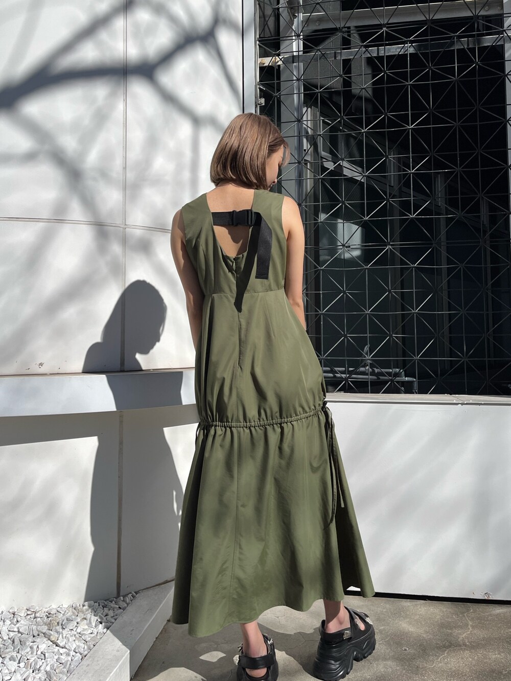 グリーン系のワンピース、ホワイト系のサンダルを着用したレディースの春コーディネートの3枚目の写真