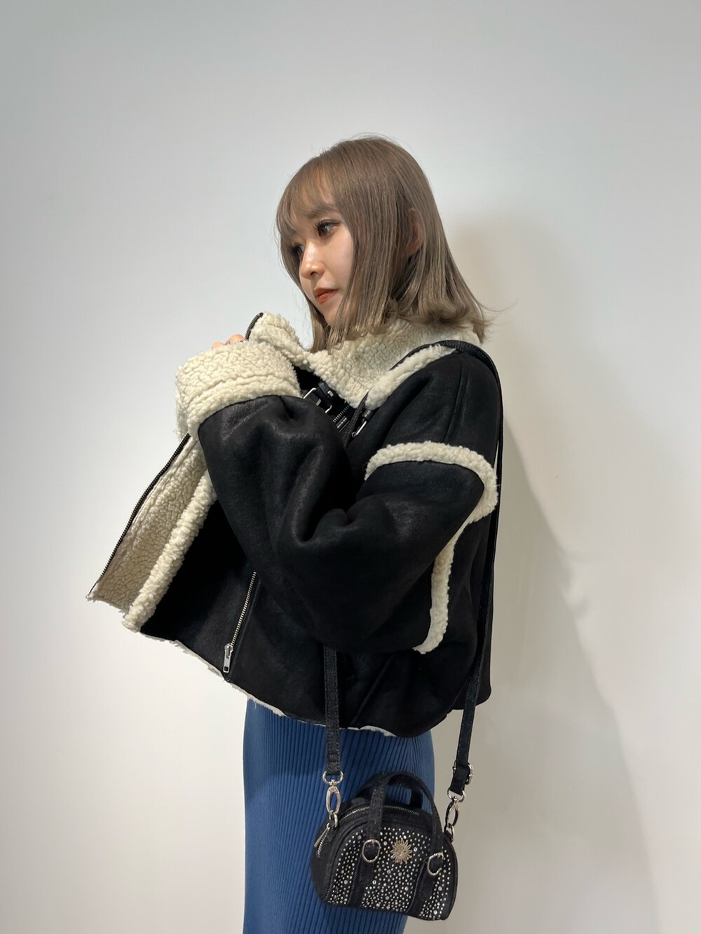 ブラック系のムートンコート、ブルー系のワンピース、ブラック系のブーツを着用したレディースの冬コーディネートの4枚目の写真