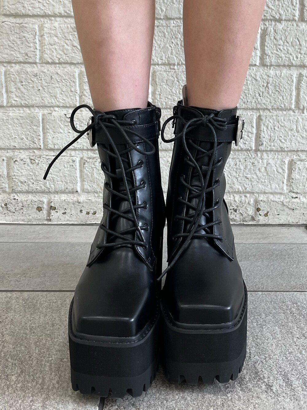 ホワイト系のパーカー、パープル系のスタジャン、ブラック系のブーツを着用したレディースの冬コーディネートの8枚目の写真