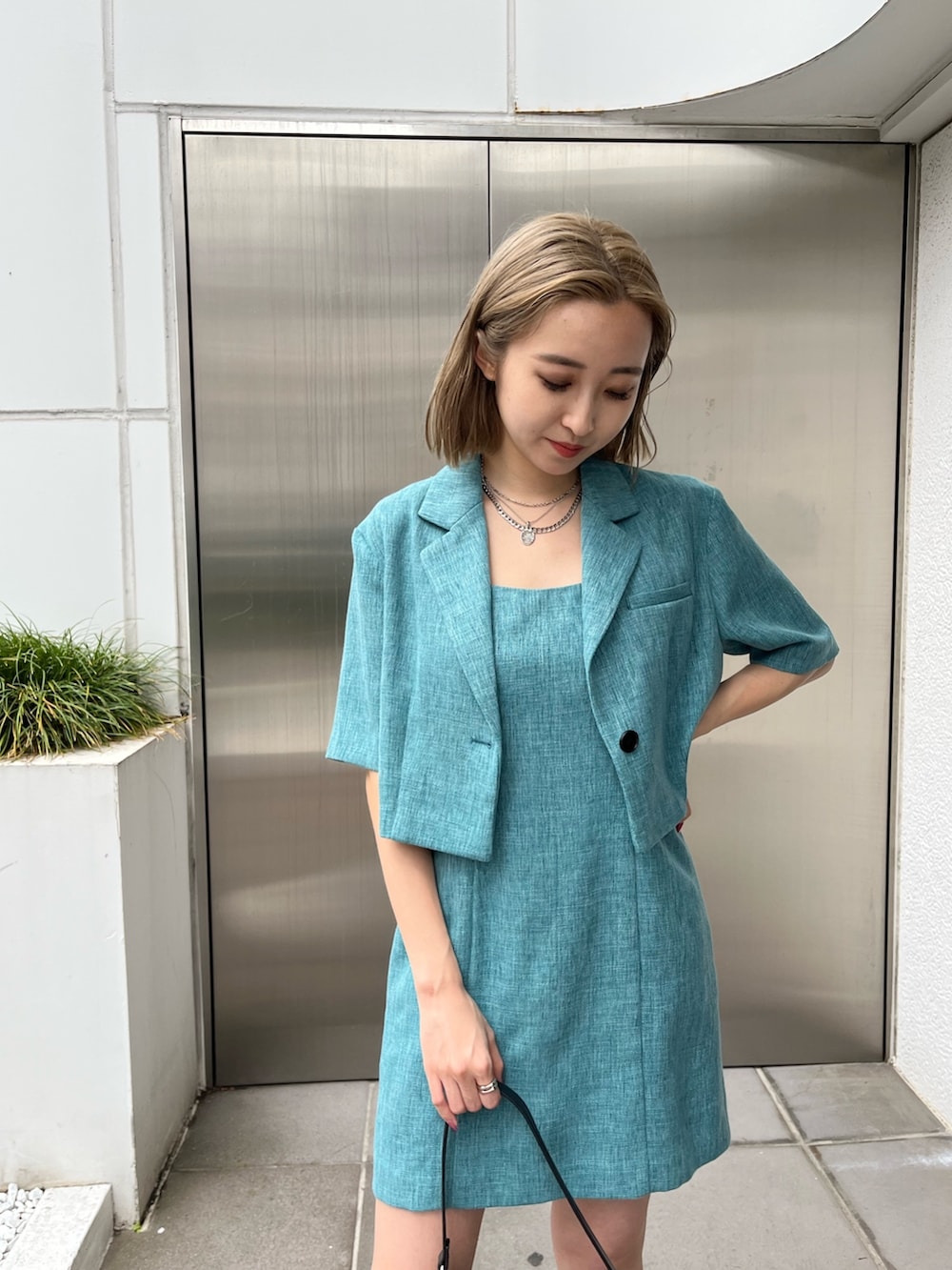 ブルー系のワンピース、グリーン系のテーラードジャケット、ホワイト系のブーツを着用したレディースの春コーディネートの6枚目の写真