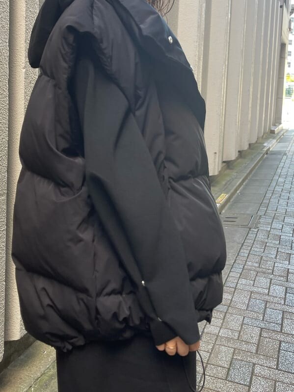 ブラック系のダウンベスト、ブラック系のワンピース、ブラック系のブーツを着用したレディースの秋コーディネートの10枚目の写真