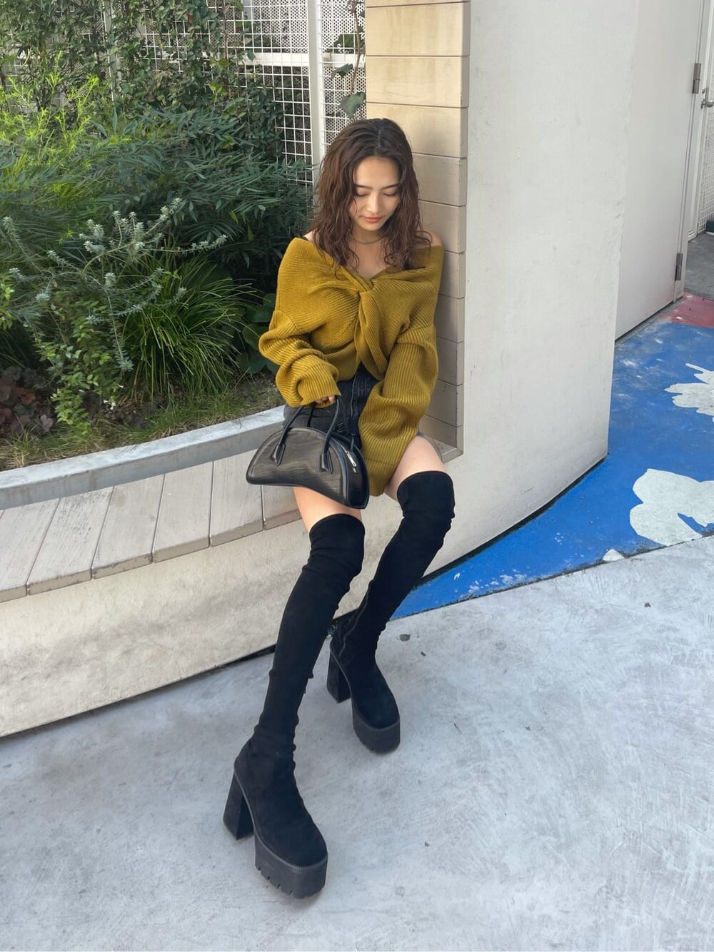 ブラック系のブーツ、ブラック系のハンドバッグ、イエロー系のニット/セーターを着用したレディースの秋コーディネートの2枚目の写真